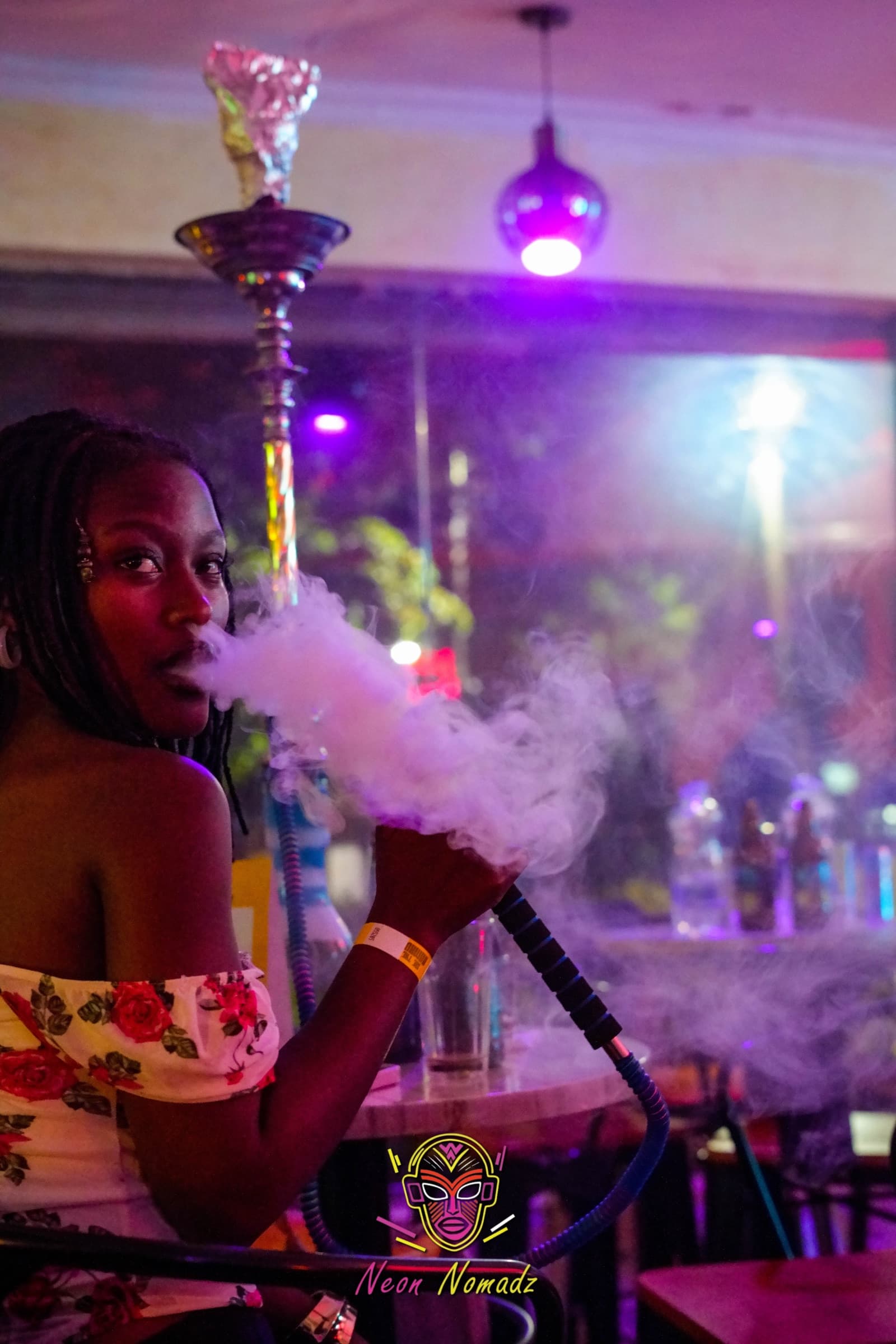 Guest at a hookah table under purple light